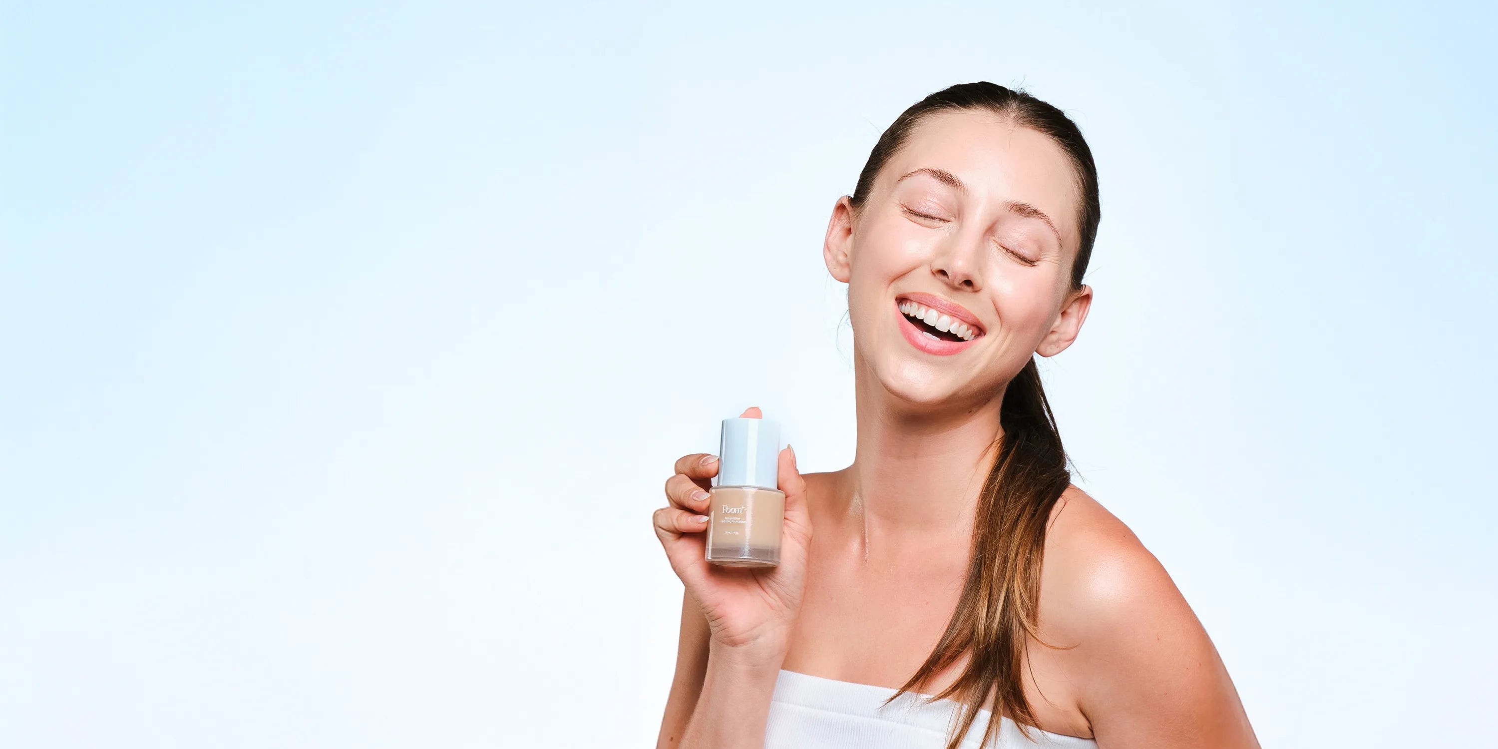 Woman holding Poom foundation bottle and smiling at the camera